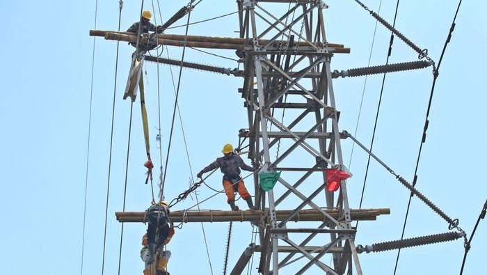 Pekerja memasang kawat penghantar pada menara Saluran Udara Tegangan Ekstra Tinggi (SUTET) di Buduran, Sidoarjo, Jawa Timur, Sabtu (19/10/2024). Pemerintah melalui Kementerian Energi dan Sumber Daya Mineral (ESDM) memutuskan tarif tenaga listrik Triwulan IV atau periode Oktober-Desember Tahun 2024 tetap atau tidak mengalami perubahan untuk 13 golongan pelanggan nonsubsidi PT PLN (Persero). ANTARA FOTO/Umarul Faruq/nym.