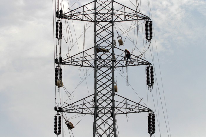 Pekerja memasang kawat penghantar pada menara Saluran Udara Tegangan Ekstra Tinggi (SUTET) di Buduran, Sidoarjo, Jawa Timur, Sabtu (19/10/2024). Pemerintah melalui Kementerian Energi dan Sumber Daya Mineral (ESDM) memutuskan tarif tenaga listrik Triwulan IV atau periode Oktober-Desember Tahun 2024 tetap atau tidak mengalami perubahan untuk 13 golongan pelanggan nonsubsidi PT PLN (Persero). ANTARA FOTO/Umarul Faruq/nym.