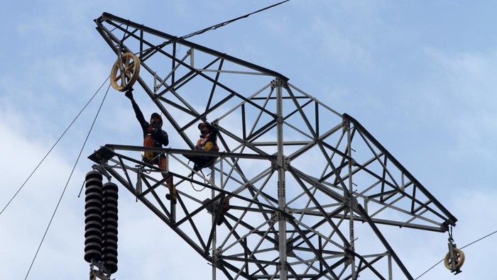 Pekerja memasang kawat penghantar pada menara Saluran Udara Tegangan Ekstra Tinggi (SUTET) di Buduran, Sidoarjo, Jawa Timur, Sabtu (19/10/2024). Pemerintah melalui Kementerian Energi dan Sumber Daya Mineral (ESDM) memutuskan tarif tenaga listrik Triwulan IV atau periode Oktober-Desember Tahun 2024 tetap atau tidak mengalami perubahan untuk 13 golongan pelanggan nonsubsidi PT PLN (Persero). ANTARA FOTO/Umarul Faruq/nym.