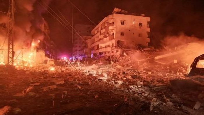 First responders work amid the fire and destruction building on fire following an Israeli airstrike that targeted the industrial zone in the southern Lebanese village of Abbasiyeh near Tyre on October 30, 2024, as the war between Israel and Hezbollah continues. (Photo by KAWNAT HAJU / AFP)