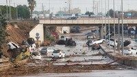 Puing-puing berserakan di sepanjang jalan dan mobil-mobil yang tersapu banjir tampak ringsek serta menutupi jalan.