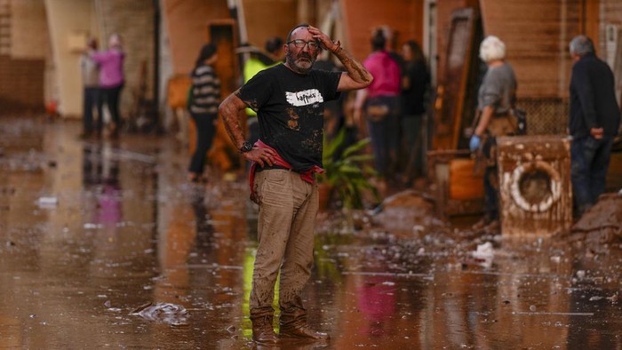 People stand among flooded cars piled up in Valencia, Spain, Thursday, Oct. 31, 2024. (AP Photo/Manu Fernandez)