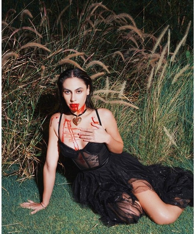 Putri Jeremy dan Ina Thomas, Valerie Thomas, memilih tampil seram mengenakan dress hitam. Dress hitam berpotongan dada rendah itu tampak memiliki aksen lace yang menerawang pada bagian perutnya. Penampilan Valerie semakin seram ditambah dengan darah palsu yang melumuri bibir dan dadanya. Foto: Instagram