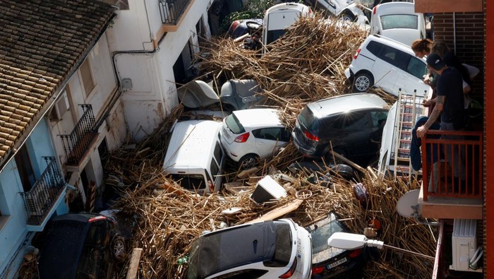 People look from a balcony at a street with piled up cars in the aftermath of torrential rains that caused flooding, in Paiporta, Spain, October 31, 2024. REUTERS/Eva Manez