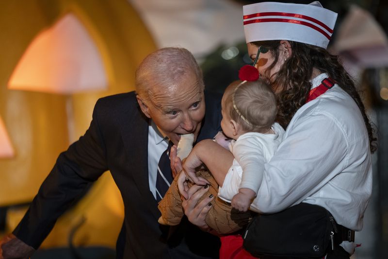 Presiden AS Joe Biden Rayakan Halloween 2025 di Gedung Putih President Joe Biden joking bites the toes of a baby, as he and first lady Jill Biden host local area students, military-connected children, and neighborhood families for trick-or-treating, ahead of Halloween on Thursday, at the South Lawn of the White House in Washington Wednesday, Oct. 30, 2024. (AP Photo/Ben Curtis)