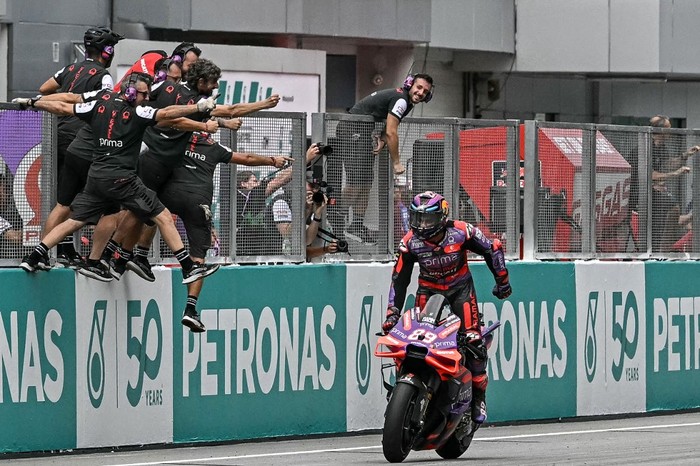 Prima Pramac Racings Spanish rider Jorge Martin celebrates as team members lean out to congratulate him for winning the Sprint race of the MotoGP Malaysian Grand Prix at the Sepang International Circuit in Sepang on November 2, 2024. (Photo by Lillian SUWANRUMPHA / AFP)