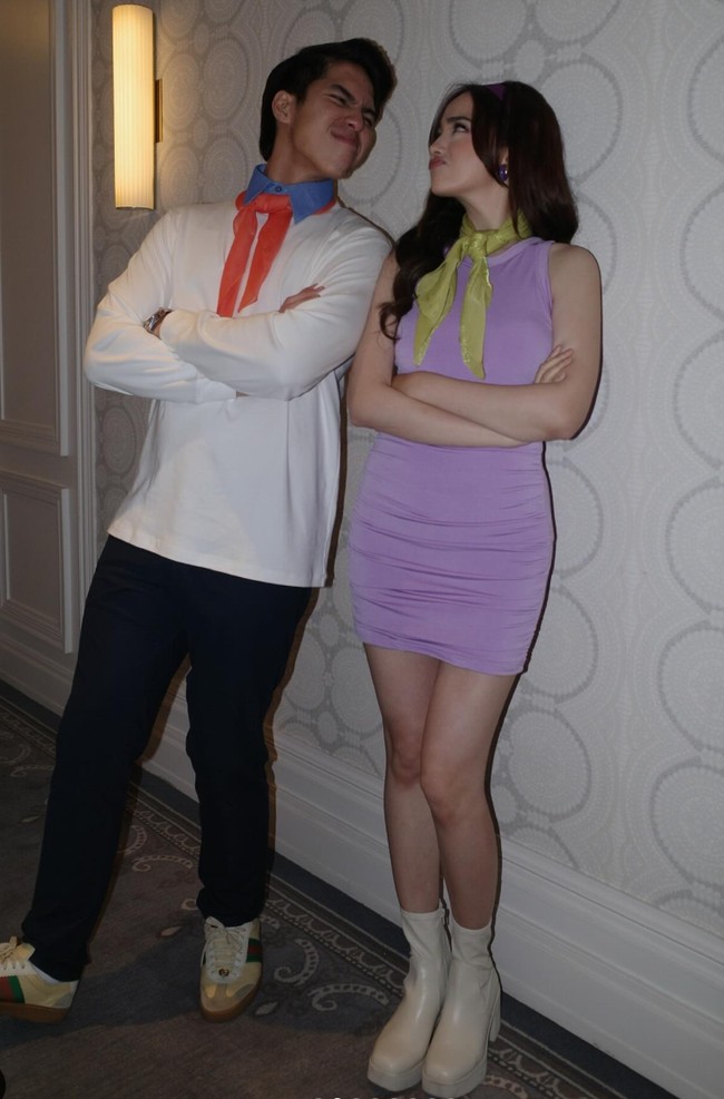 El dan Syifa terlihat menggemaskan cosplay menjadi karakter dalam film Scooby Doo. El mengenakan kaos lengan panjang putih dipadukan dengan celana hitam, lengkap dengan kerah biru dan pita oranye di lehernya. Sementara Syifa mengenakan mini dress ungu lengkap dengan pita hijau di lehernya. Tak lupa ia juga mengenakan bandana berwarna ungu khas karakter Daphne. Foto: Instagram/@wanda_haraa