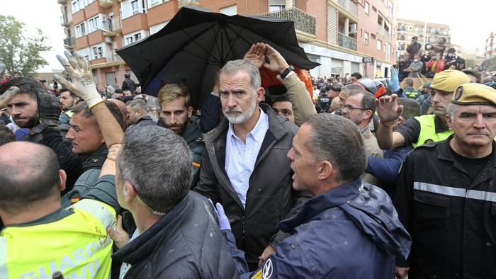 Spains King Felipe VI is protected after a crowd of angry survivors of Spains floods have tossed mud and shouted insults at the King and government officials when they made their first visit to one of the hardest hit towns after floods in Paiporta near Valencia, Spain, Sunday, Nov. 3, 2024. (AP Photo/Hugo Torres)