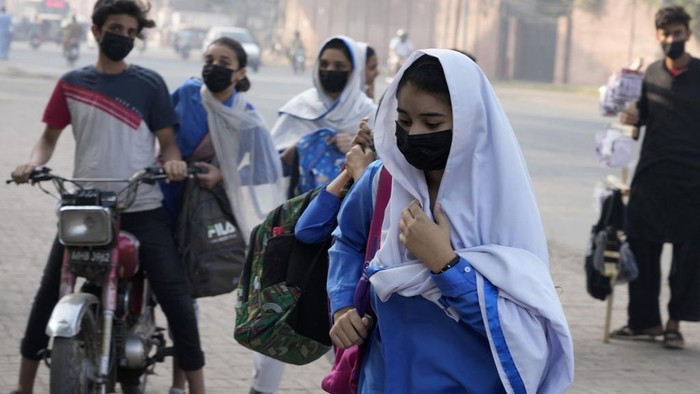 A teacher and students wear mask to protect themselves from poor air quality due to increasing smog in the city as they attend their school, in Lahore, Pakistan, Monday, Nov. 4, 2024. (AP Photo/K.M. Chaudary)
