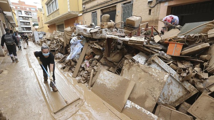 A woman sweeps away mud after floods in Paiporta, near Valencia, Spain, Sunday, Nov. 3, 2024. (AP Photo/Hugo Torres)