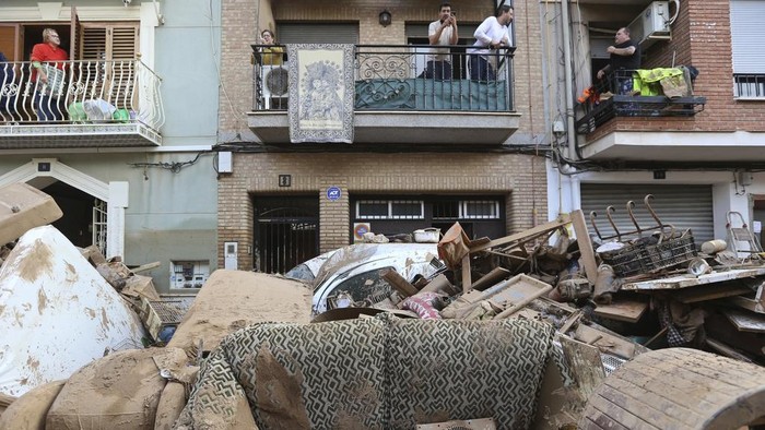 Residents stand on their balconies above destroyed furniture below after floods in Paiporta, near Valencia, Spain, Sunday, Nov. 3, 2024. (AP Photo/Hugo Torres)