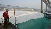 Tampak pekerja dari pemerintah daerah menyemprotkan bahan kimia untuk melarutkan busa beracun di atas Sungai Yamuna.  