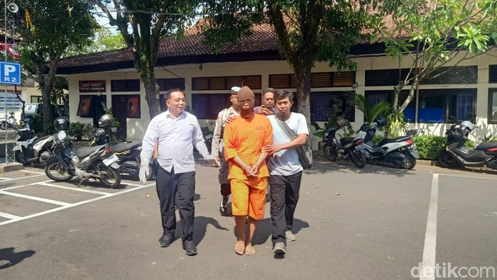 Pria berinisial AGD yang menjadi tersangka tindak pidana persetubuhan digiring petugas kepolisian di Mapolres Jembrana, Senin (4/11/2024). (Foto: I Putu Adi Budiastrawan/detikBali)