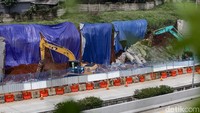 Ada juga truk pengangkut puing yang terparkir di bahu jalan. Tampak tanggul yang jebol itu ditutupi dengan terpal. Arus lalu-lintas terpantau lancar.  