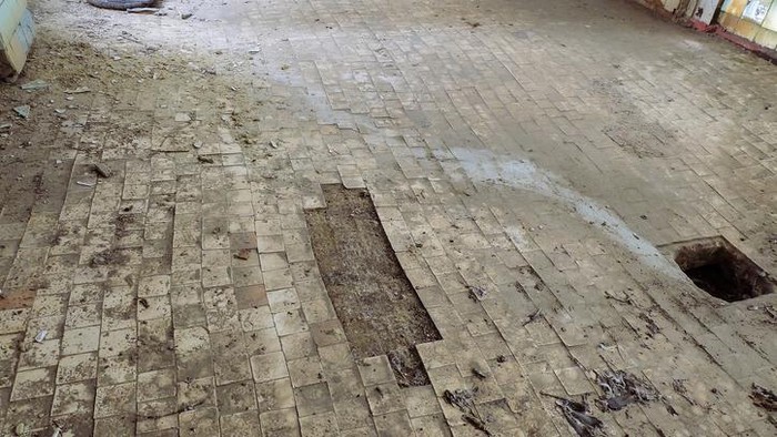 Destroyed concrete flooring with tile surface due to subsidence of the base soil