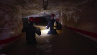 Para petugas mengevakuasi basement dengan bantuan lampa senter dan perlengkapan yang mendukung.