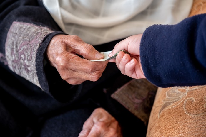 Hands of old woman giving money to her grandson during arabia eid