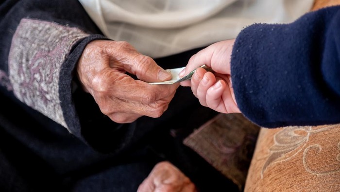 Hands of old woman giving money to her grandson during arabia eid