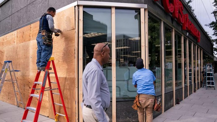 Workers cover the windows of a pharmacy near the White House with plywood ahead of the U.S. presidential election in Washington, U.S., November 4, 2024. REUTERS/Nathan Howard Purchase Licensing Rights