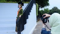 Warga berpose untuk foto wisuda di Lapangan Banteng, Jakarta, Selasa (05/11/2024).