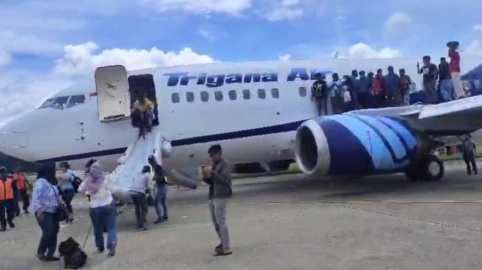 Penumpang di Bandara Sentani turun dari pesawat usai ada percikan api dari mesin pesawat Trigana Air.
