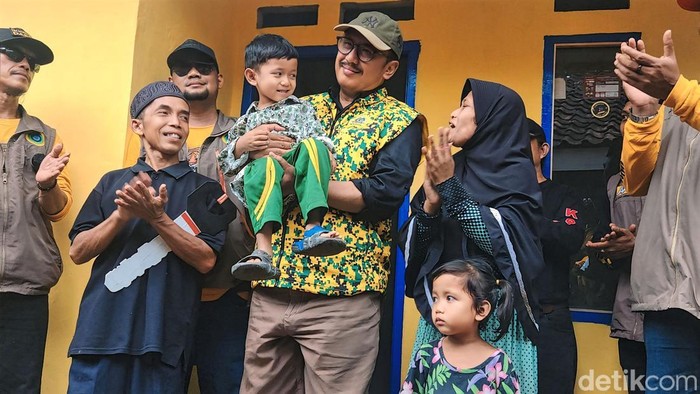 Agus Acil (kemeja hitam) tersenyum bahagia usai rumahnya dibuat layak huni.