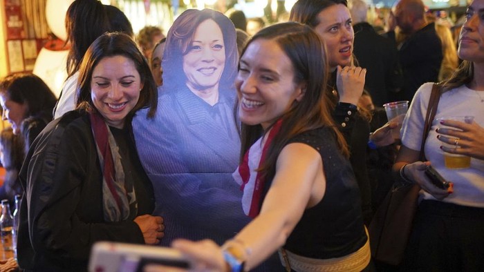 People pose for photos with a cardboard cutout of U.S. Democratic presidential candidate Vice President Kamala Harris at the Democrats Abroad US election watch party in central London on Tuesday, Nov. 5, 2024. (Yui Mok/PA via AP)