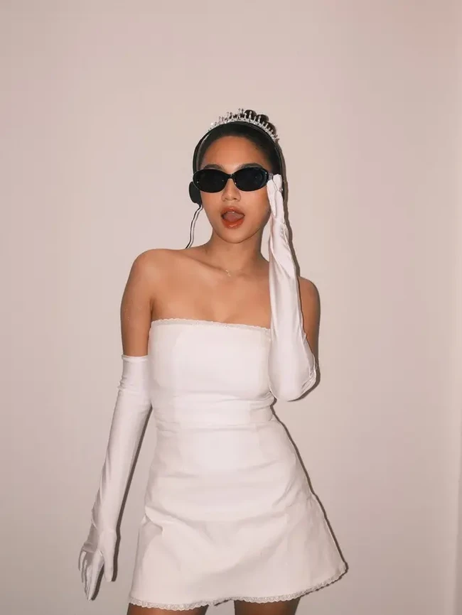 Azizah Salsha tampil slay mengenakan mini tube dress putih dipadukan dengan sarung tangan putih dan kaca mata hitam. Tak lupa ia juga melengkapi penampilannya dengan headphone dan mahkota di kepala. Foto: Instagram