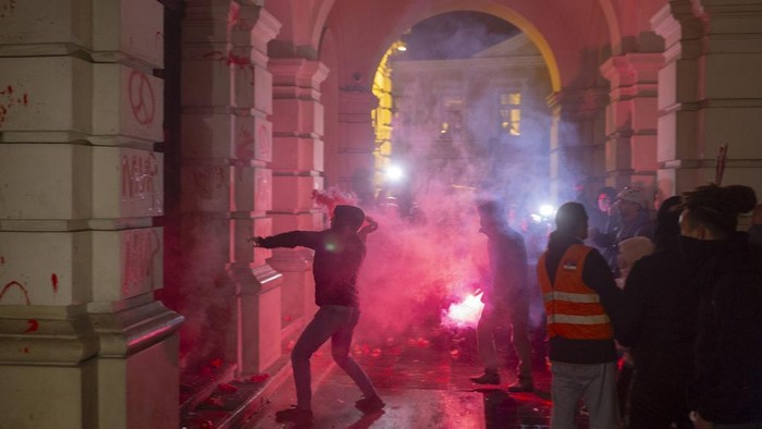 A protester points at riot police as they cover inside the City Hall building during a protest in rage over last week's collapse of a concrete canopy at the railway station that killed 14 people, in Novi Sad, Serbia, Tuesday, Nov. 5, 2024. (AP Photo/Marko Drobnjakovic)