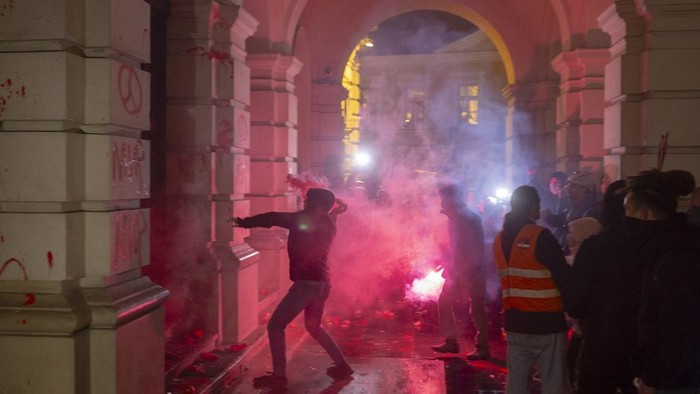 Marah Soal Tragedi Atap Stasiun Runtuh, Warga Serbia Rusak Balai Kota A protester points at riot police as they cover inside the City Hall building during a protest in rage over last week's collapse of a concrete canopy at the railway station that killed 14 people, in Novi Sad, Serbia, Tuesday, Nov. 5, 2024. (AP Photo/Marko Drobnjakovic)