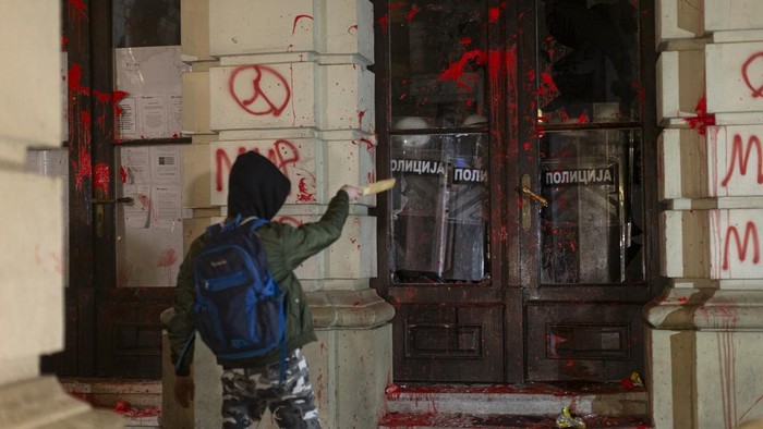 A protester points at riot police as they cover inside the City Hall building during a protest in rage over last week's collapse of a concrete canopy at the railway station that killed 14 people, in Novi Sad, Serbia, Tuesday, Nov. 5, 2024. (AP Photo/Marko Drobnjakovic)