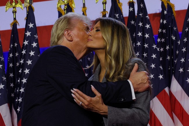Salah satu momen yang paling disorot adalah ketika Donald Trump mencoba memeluk dan mencium Melania di atas panggung. Darren mencatat bahwa Melania tampak enggan melakukannya hingga terlihat canggung.  Foto: REUTERS/Brian Snyder
