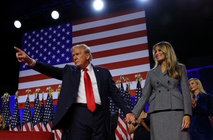 Republican presidential nominee and former U.S. President Donald Trump gestures as he holds hands with his wife Melania during his rally, at the Palm Beach County Convention Center in West Palm Beach, Florida, U.S., November 6, 2024. REUTERS/Brian Snyder     TPX IMAGES OF THE DAY