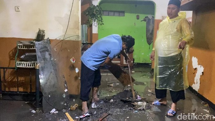 Warga Sukabumi tengah membersihkan rumahnya yang terkena banjir