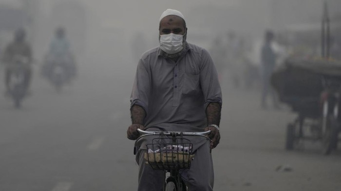 A cyclist, wearing mask, heads to his workplace as smog envelops the areas of Lahore, Pakistan, Wednesday, Nov. 6, 2024. (AP Photo/K.M. Chaudary)