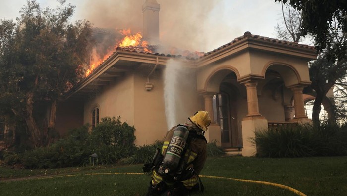 A firefighter works to stop a fire at a building, as smoke billows from the Mountain Fire in Camarillo, California, U.S., November 6, 2024. REUTERS/David Swanson