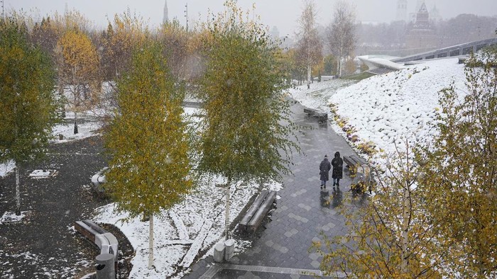 A man walks at Zaryadye park with the Spasskaya tower of the Kremlin and St. Basil's Cathedral in the background during a snowfall in Moscow, Russia, Wednesday, Nov. 6, 2024. (AP Photo/Pavel Bednyakov)