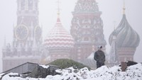 Seorang pria berjalan di taman Zaryadye dengan menara Spasskaya Kremlin dan Katedral St. Basil di latar belakang saat hujan salju di Moskow, Rusia, Rabu (6/11/2024).