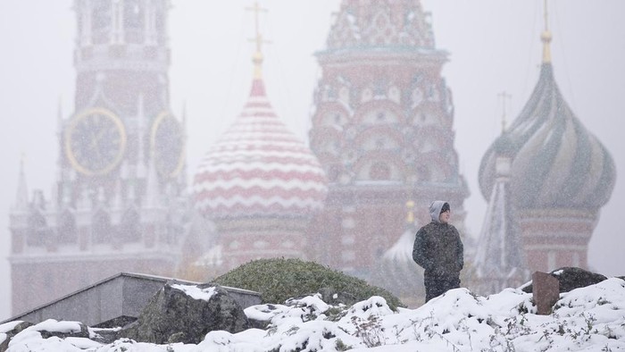 A man walks at Zaryadye park with the Spasskaya tower of the Kremlin and St. Basil's Cathedral in the background during a snowfall in Moscow, Russia, Wednesday, Nov. 6, 2024. (AP Photo/Pavel Bednyakov)
