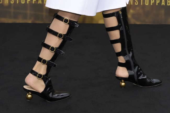 J.Lo terlihat memakai boots selutut berdetail gesper di sepanjang betis yang terkesan edgy. Foto: Scott A Garfitt/Invision/AP