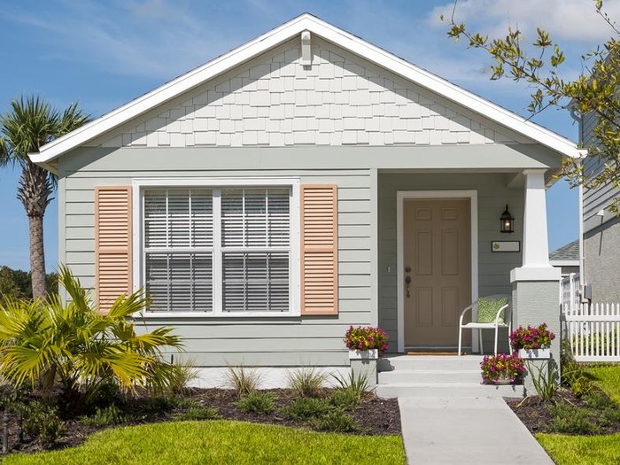Tidy little cottage with shutters, flowers, front yard and sidewalk. Affordable home; modest house. Space for copy.