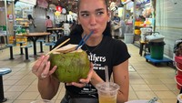 Posenya saat menikmati air kelapa ini sukses mencuri perhatian. Ia tampak antusias saat minum air kelapa langsung dari batoknya. Foto: Instagram @dualipa