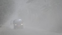 Pengendara mobil melintasi Jalan Trans Flores yang tertutup material pasir vulkanis dari erupsi Gunung Lewotobi Laki-laki di Desa Dulipali, Ilebura, Kabupaten Flores Timur, Nusa Tenggara Timur, Sabtu (9/11/2024).