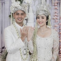 Kebaya putih klasik yang dikenakan Febby merupakan rancangan dari desainer Vera Kebaya. Kebaya brukat tersebut dipadukan dengan kain lilit berwarna coklat. Foto: Bridestory
