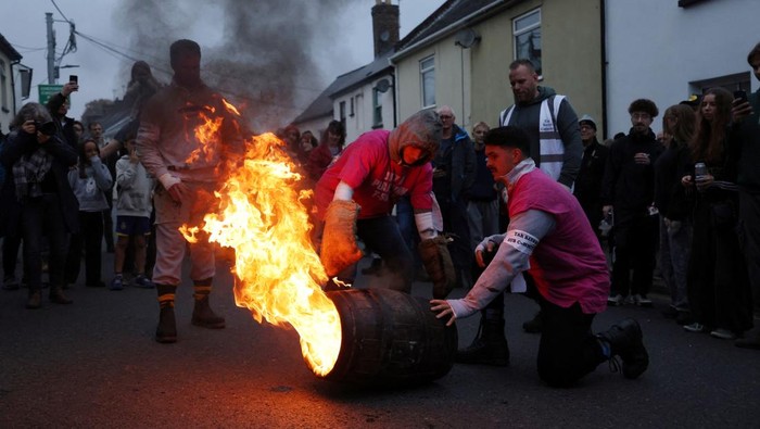 A teenager carrying a flaming tar barrel runs through the street in Ottery St. Mary on Guy Fawkes night in Britain, November 5, 2024. REUTERS/Hollie Adams