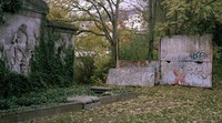 Sisa-sisa Tembok Berlin berdiri di samping makam di sebuah pemakaman di Berlin Tengah, Jerman. Sebagian besar perbatasan Jerman Timur yang dibentengi dengan kuat dirobohkan dengan cepat setelah dibuka pada tahun 1989, tetapi masih ada tempat-tempat di mana pengunjung dapat melihat sisa-sisa Tembok Berlin dan bagian lain dari perbatasan tersebut.