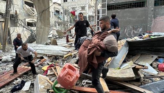 A man lies on a body in the back of a pickup truck, in the courtyard of the al-Shifa hospital in Gaza City after victims were transported there, following an Israeli strike that hit a school-turned-shelter in the Al-Shati refugee camp on November 7, 2024, amid the ongoing war between Israel and the Hamas militant group. (Photo by Omar AL-QATTAA / AFP)