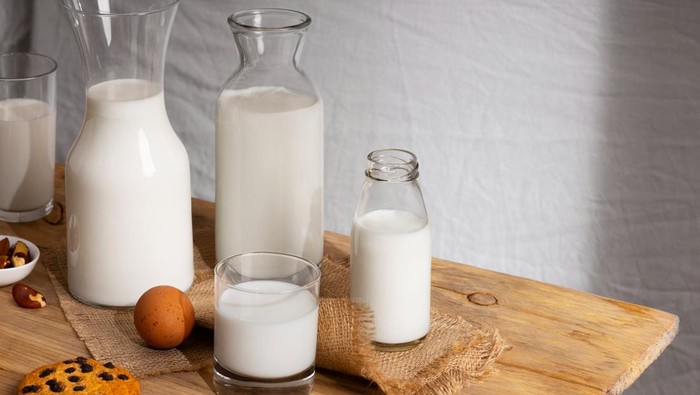Susu murni di botol dan gelas di atas meja