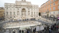Orang-orang berjalan di sepanjang jalur khusus di Air Mancur Trevi, Roma, Italia, Minggu (10/11/2024). (AP Photo/Gregorio Borgia)