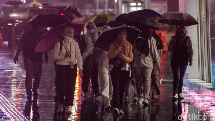 Warga berjalan menggunakan payung saat hujan mengguyur kawasan Jalan Sudirman, Jakarta, Senin (11/11/2024).